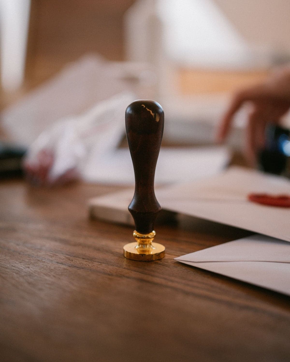 A brass seal stamp resting on a desk beside sealed envelopes